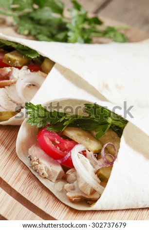 Shawarma, turkish doner kebab, roll with meat and pita bread on a wooden background, selective focus