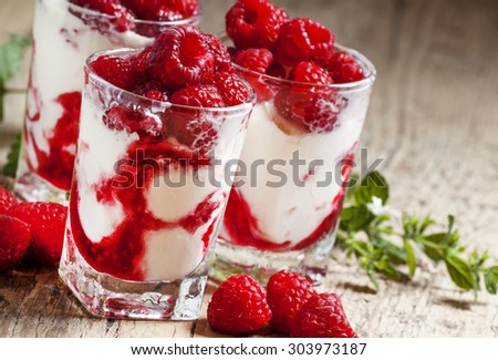 Raspberry ice cream with berries and mint, served in glasses on an old wooden table, selective focus