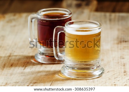 Light and dark beer in old-fashioned circles on old wooden table, selective focus