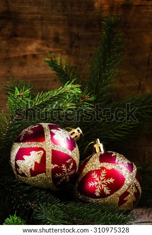 Two red and gold Christmas ball and spruce branches on an old wooden background, selective focus