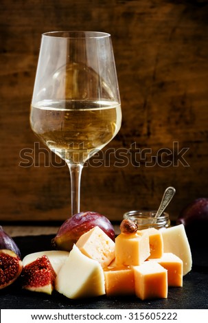 White wine, cheese, figs, nuts and grapes on the old wooden background, still life, selective focus