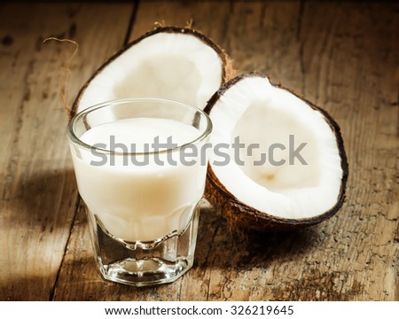 Coconut milk and fresh coconut on the old wooden background, selective focus