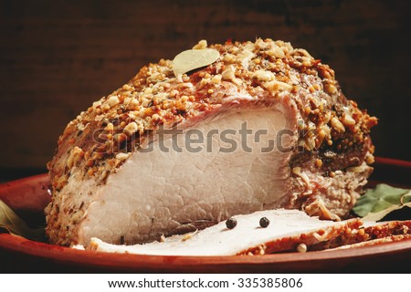 Delicious baked ham pork on a clay tray on the old wooden background, selective focus