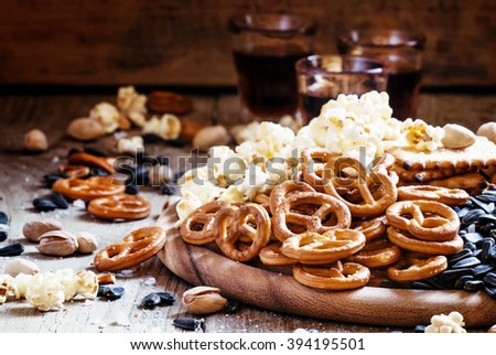 Salted straws in the shape of pretzels, popcorn and other salty snacks, junk food, snacks, for beer or cola, old wooden background, selective focus