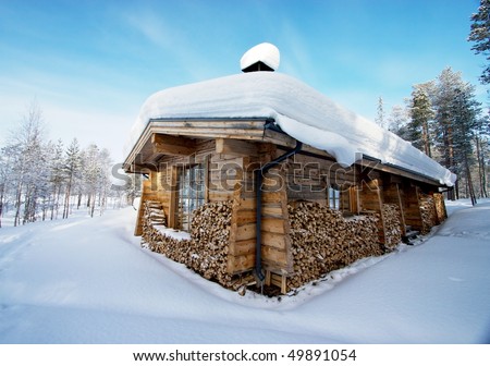 Snow-covered wooden house in forest, with a log fire for winter and plenty of fuel