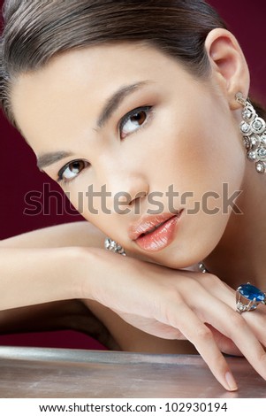 Attractive young woman with diamonds on the hand looking to the camera on the red background