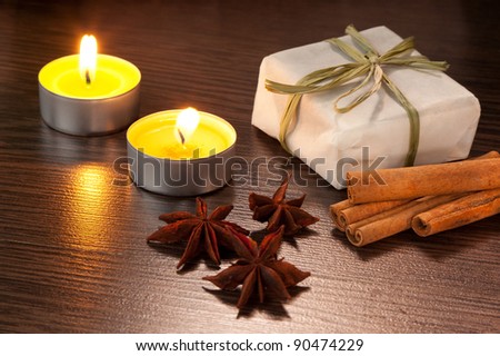 Candle, cinnamon sticks and anise stars with candle on table