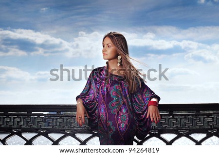 Attractive young woman in violet dress looking out the camera near the river in sunny day