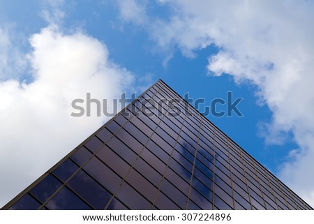 clouds and sky are reflected in the mirrored window constructed in high-tech style building