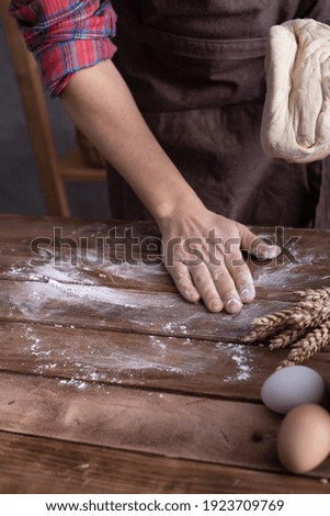 Baker man kneading dough and bakery ingredients for homemade bread cooking on table. Bakery concept with male hand and dough wooden tabletop background texture