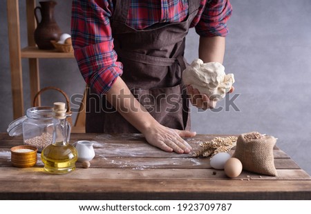 Baker man kneading dough and bakery ingredients for homemade bread cooking on table. Bakery concept near wall background texture