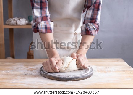 Baker man kneading or making dough and bakery ingredients for homemade bread cooking on shelf. Bakery concept near wall background texture