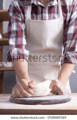 Baker man kneading or making dough and bakery ingredients for homemade bread cooking on shelf. Bakery concept near wall background texture