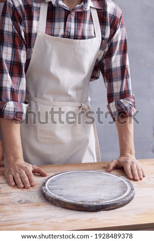 Baker man and pizza board and bakery ingredients for bread cooking on shelf. Bakery concept near wall background texture