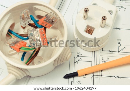 Electrical box with connections of electric wires and plug with construction drawing of house. Components using in electrical installations. Accessories for engineering work