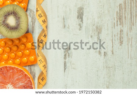 Fresh natural fruits containing vitamins, tape measure and medical pills. Choice between healthy nutrition and supplements. Copy space for text or inscription