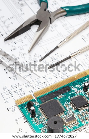 Printed circuit board with transistors, resistors, capacitor. Precision tools and diagram of electronics. Technology