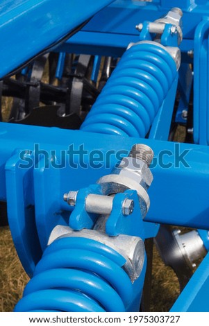 Big and hard blue steel spring as part and detail of industrial or agricultural machine. Technology
