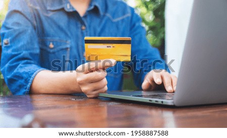 Closeup image of a woman holding credit cards while using laptop computer for online shopping