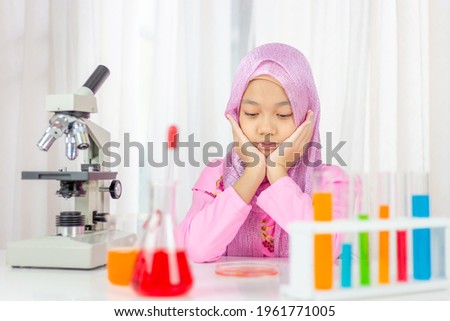 Muslim girl in elementary school in a science lab experiment, Islamic kindergarten students are playing a lab scientist with blurred microscopy, Kids and education concepts.
