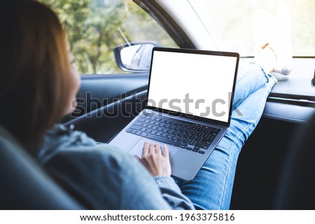 Mockup image of a woman using and working on laptop computer with blank desktop screen in the car