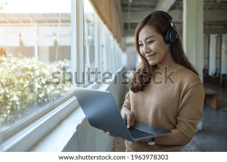 A beautiful young asian woman with headphone using and working on laptop computer