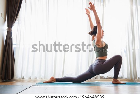 Asian woman in sports clothing doing yoga at home to quarantine herself from Covid-19, New normal lifestyle concept. Healthy lifestyle. Relaxing at home