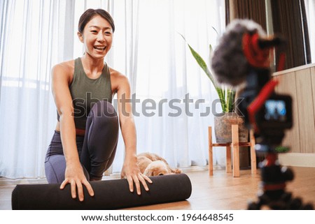 Asian woman yoga teacher filming yoga online class on video for Social media. Professional instructor in sportswear posing on VIDEO camera. Healthy lifestyle - technology at home. New normal lifestyle