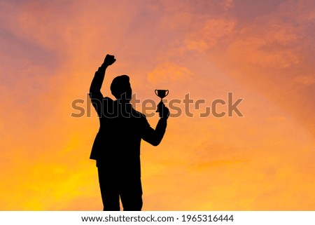 Silhouette of Business man holding award trophy show victory when business success sunset background
