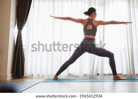 Asian woman in sports clothing doing yoga at home to quarantine herself from Covid-19, New normal lifestyle concept. Healthy lifestyle. Relaxing at home