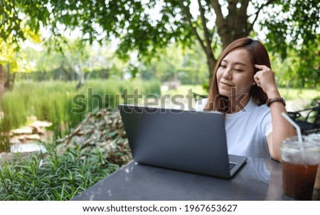 A young asian woman thinking about work while using laptop computer in the outdoors