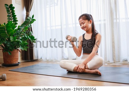 Little Girl doing exercise at home on a yoga mat in the living room at home. New normal concept. Healthy lifestyle. Relaxing at home