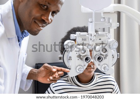 African young woman girl doing eye test checking examination using phoropter in clinic or optical shop. Eyecare concept.