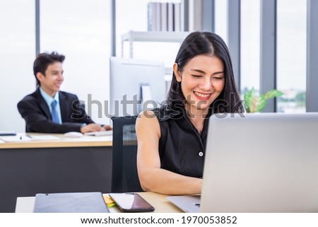 Young Asian woman sitting at office desk and working with laptop computer. Businesspeople or salary man life.