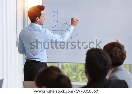 Rear view businessman coaching in team meeting or training, speaker drawing graph on white board (business seminar concept)