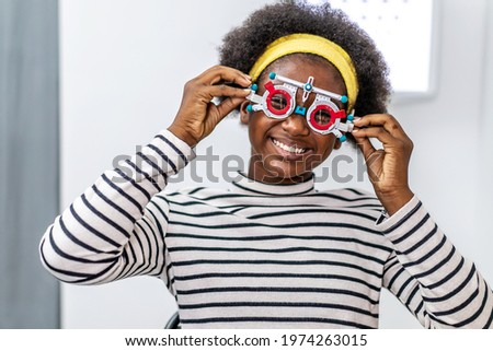Smiling young woman african american checking vision with eye test glasses during a medical examination at the ophthalmological office, Checking eye vision by optician health examination concept