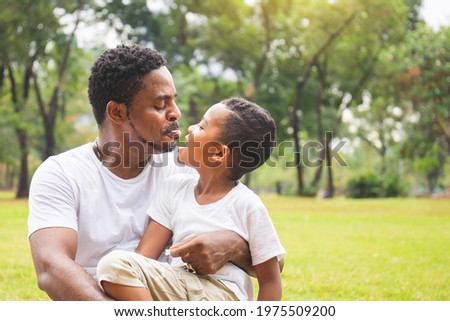 Cheerful African American father and son are eating snack in the park, Happiness family having a picnic