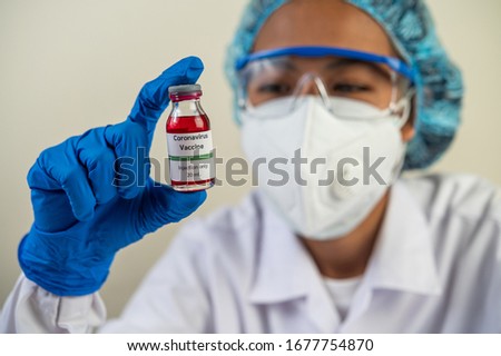 Scientists wearing masks and gloves, carrying vials with vaccines to protect Covid-19