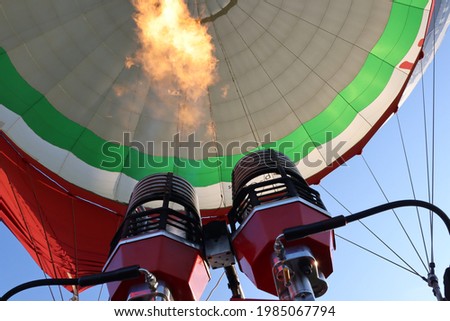 A low angle shot of the engines of a hot-air balloon shooting fire up into the air