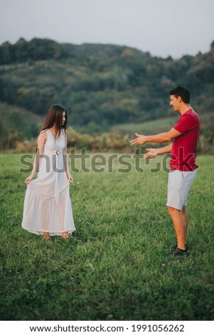A young Caucasian couple enjoying their time on beautiful mountain covered by green grass