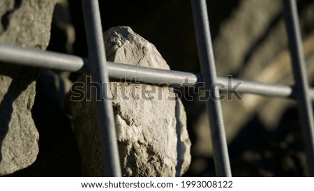 A wide-angle shot of rocks behind a metal grid for wallpaper and background