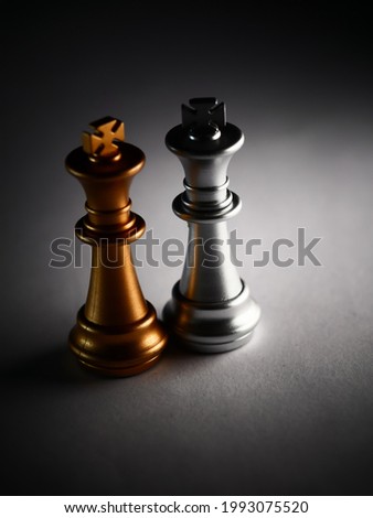 A vertical closeup shot of silver and gold king chess pieces