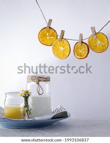 A vertical shot of dried oranges hanging on a string over jars of orange juice and sugar