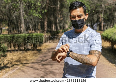 A Hispanic man with a tattoo sleeve wearing sportswear, a black mask, and a watch