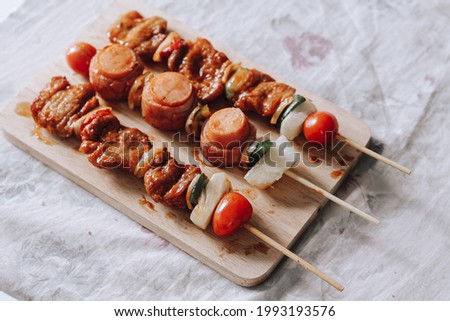 A shot of juicy skewers with meat and vegetables on a wooden board and a marble tabletop