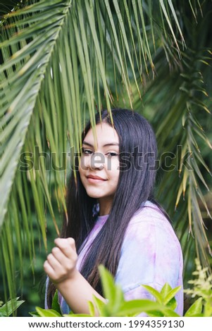 A vertical shot of a cute young Caucasian lady wearing a multicolored t-shirt in nature