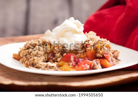 A closeup shot of homemade plum and peach crumble or cobbler with whipped cream