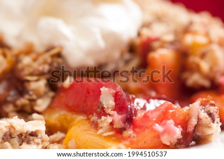 A closeup shot of home made plum and peach crumble or cobbler with whipped cream