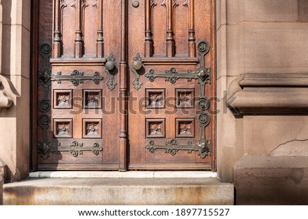 Old wooden exterior doors with decorative panels, brass doorknobs and details.