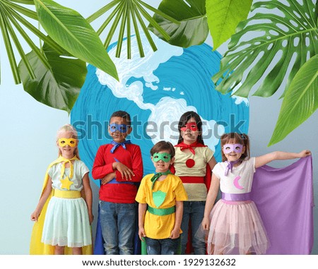 Cute little children dressed as superheroes near drawing of planet on color background. Earth Day celebration